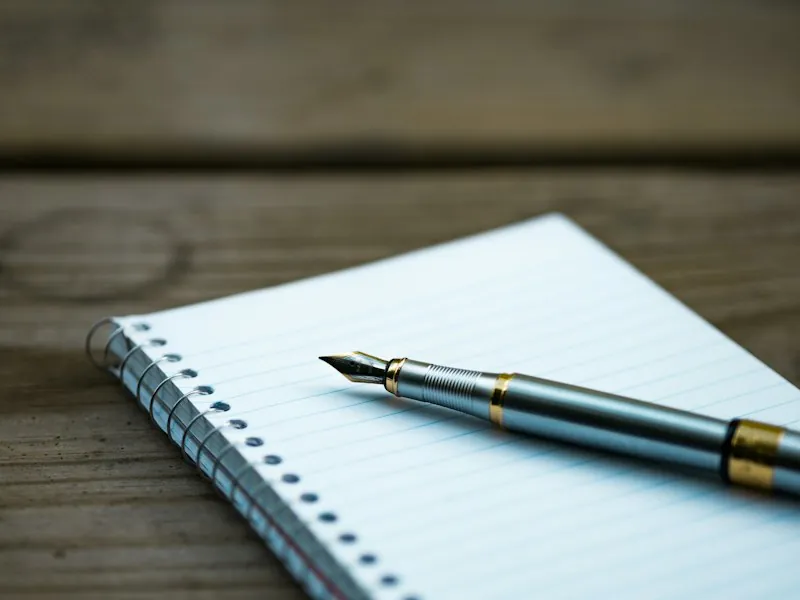 Silver fountain pen resting on a notebook