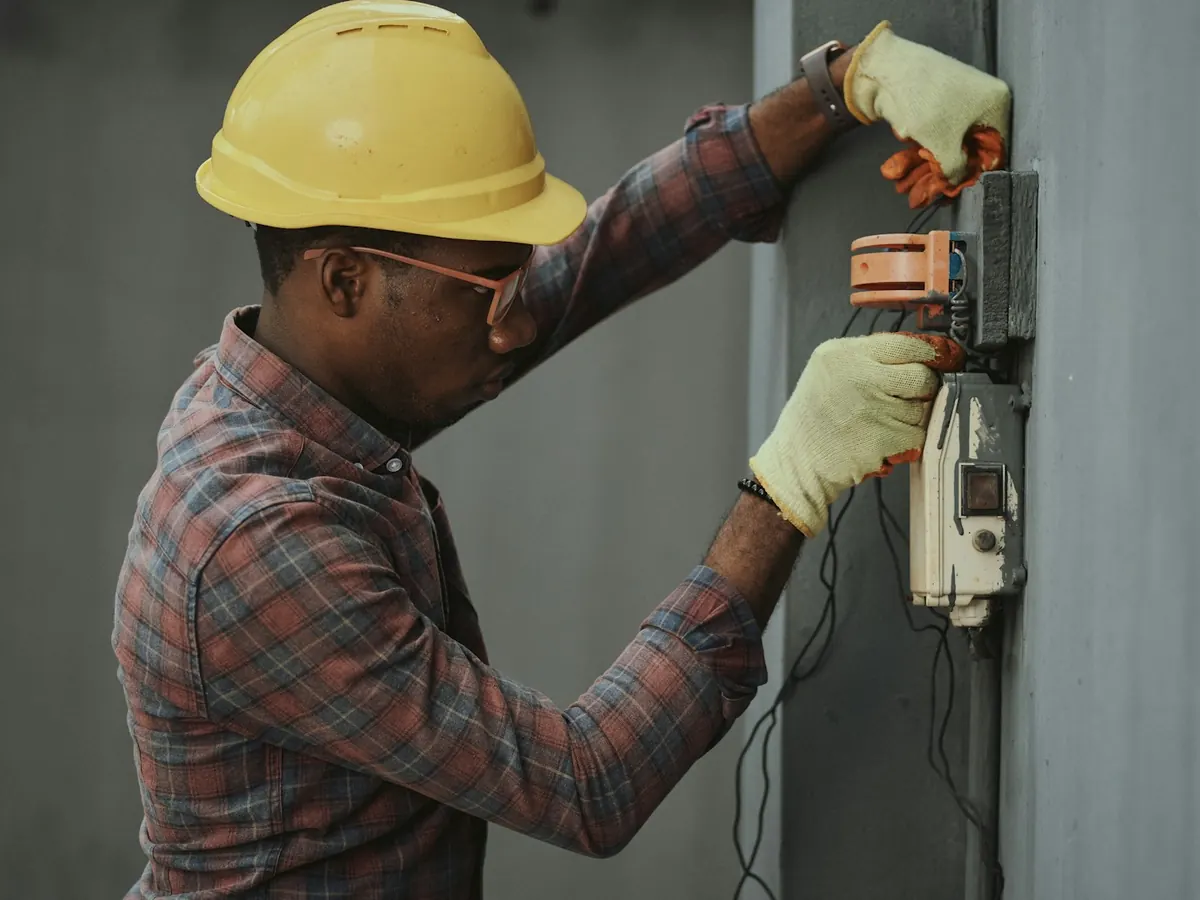 Technician in a hard hat working on an electrical panel
